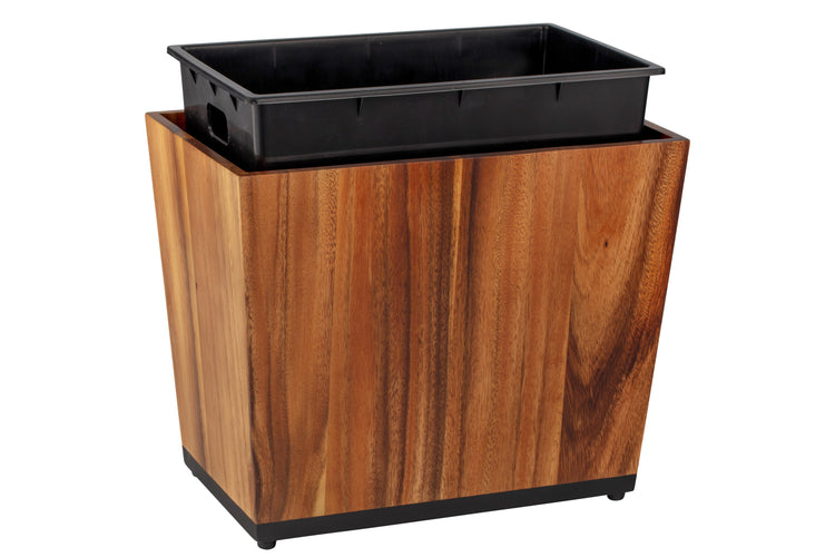 Acacia | Taniya Nayak wood wastebasket with the full liner propped up on a white background.